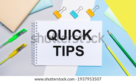 On a gray and blue background are stationery of yellow-green color, a notebook with the text QUICK TIPS. Flat lay.