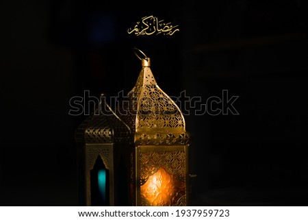 Ornamented Arabic lanterns glowing on a dark background. Ramadan concept image. Free space for your text. Translation of Ramadan kareem means 'Blessed Ramadan'.