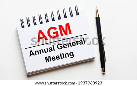 On a light background, a white notebook with are words AGM Annual General Meeting and a pen. Royalty-Free Stock Photo #1937960923
