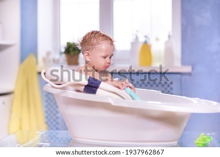 Red-haired baby boy takes a bath. Playing with toys.
