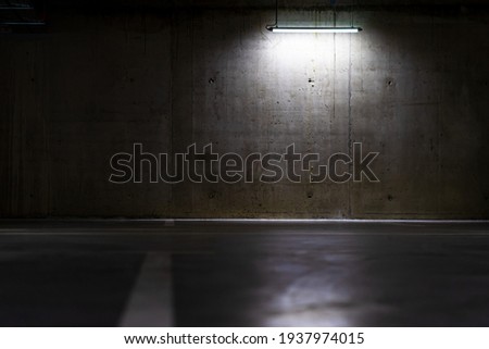 Empty parking lot with overhead dim light, underground parking garage. Royalty-Free Stock Photo #1937974015