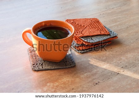 A cup of coffee and crocheted napkins square shaped. Napkins under hot	