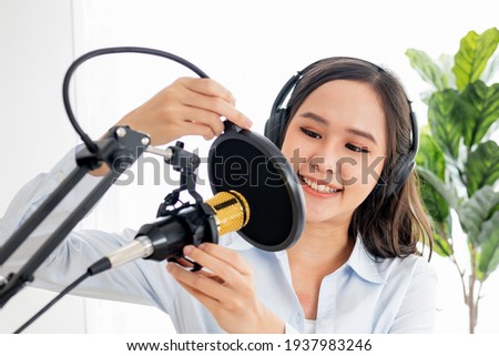 Smile young asian woman radio host working, wearing headphones, setting microphone, preparing to speak before recording podcast and live on social media. On-air online in broadcasting at studio.