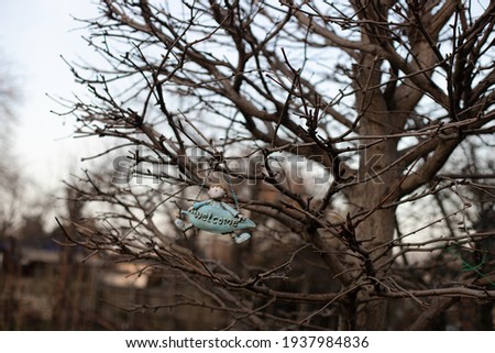 A spring welcome sign hanging on a tree branch. A seasonal vintage picture with blurred background. Stock photography.
