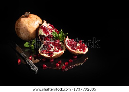 Pomegranate juice in a glass and pomegranate slices on a dark background. Vitamin drink. Still life.