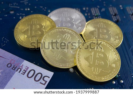Banknote and Golden and silver coins with bitcoin symbol on a mainboard, symbol of new money