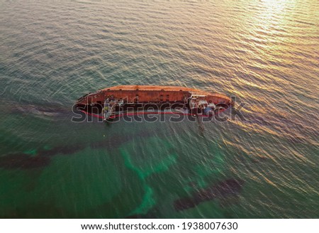 The old rusty ship was stranded by a storm. Oil spill from a tanker, environmental pollution. Ship at sunrise Royalty-Free Stock Photo #1938007630