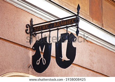 Forged old street sign. Scissors and a boot and an inscription - a shoemaker and a tailor in Polish.