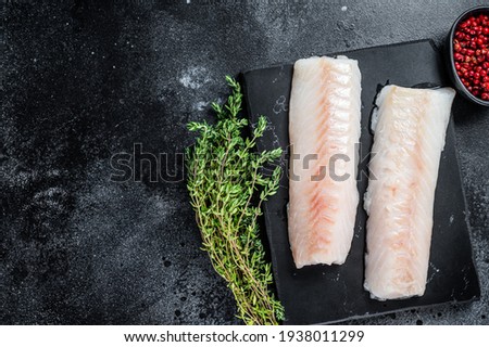 Raw cod loin fillet fish on marble board. Black background. Top view. Copy space Royalty-Free Stock Photo #1938011299