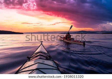 Adventurous Man Sea Kayaking in the Pacific Ocean. Dramatic Colorful Sky Art Render. Taken in Jericho, Vancouver, British Columbia, Canada. Royalty-Free Stock Photo #1938011320