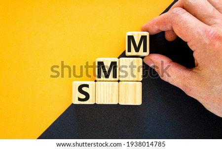 SMM, social media marketing symbol. Wooden cubes with word 'SMM, social media marketing' on beautiful yellow background, copy space. Businessman hand. Business, SMM - social media marketing concept.