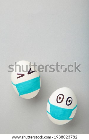White Easter eggs in protective medical mask on grey background. Easter on quarantine concept with place for text. Stop VIRUS COVID-19. Copy space. Egg in mask. Top view