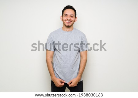 Portrait of a happy latin man smiling and wearing a mock up gray t-shirt. Attractive man in a t-shirt for design print