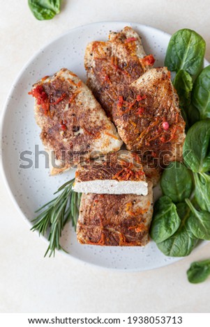 Fried turkey or chicken breast served with orange sauce, spinach and rosemary on a plate, light concrete background. Healthy balanced food. Selective focus. Top view.