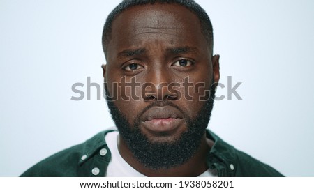 Portrait of offended african american man looking at camera in studio. Displeased african guy posing on light background. Closeup disappointed guy face. Handsome afro man face with unhappy emotion.
