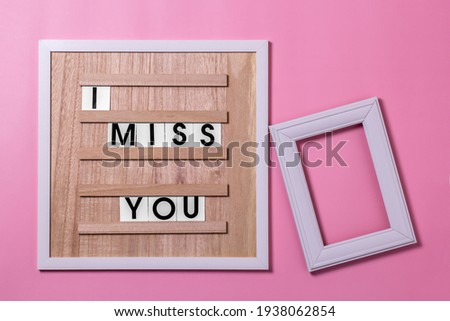 lettering on the quote board I miss you with a photo frame on a pink background. the concept of love at a distance.