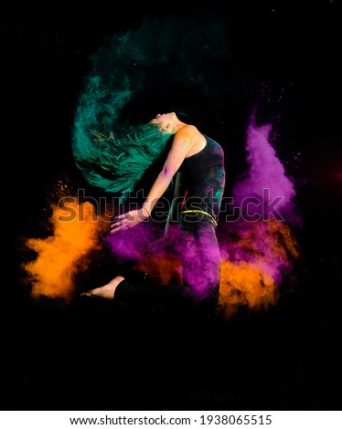 young woman makes a high jump with a explosion of dry colorful holi powder. Holi festival india at night Royalty-Free Stock Photo #1938065515