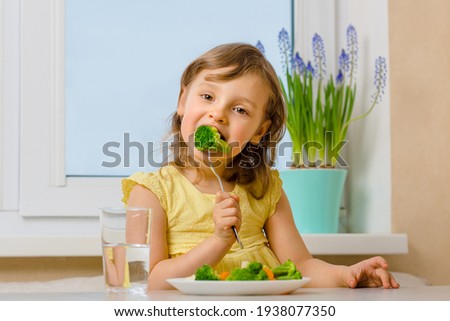 The child eats broccoli with an appetite. Organic Cabbage and food on a plate. Green healthy vegetables rich in vitamins. Proper nutrition concept. Royalty-Free Stock Photo #1938077350