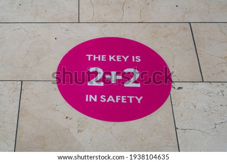 2+2 sign on the shopping mall floor. Rules about safe shopping. Need to keep distance. Max 2 people together. Big pink sign on the floor in the mall. Not the cleanest floor