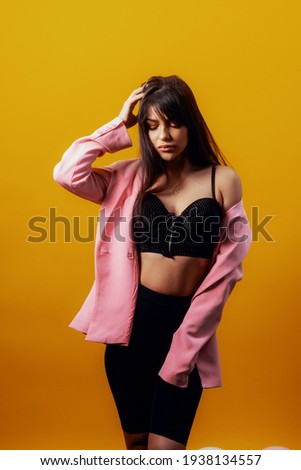 Stunning long haired female model posing with different face expression on yellow background. Close-up portrait of stylish european girl standing with peace sign in front of wall.
