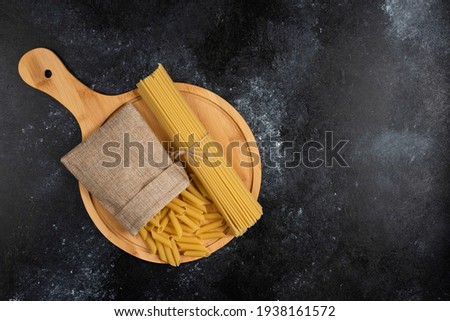 Penne pasta in a rustic basket with spaghetties on a wooden platter