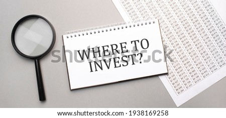 Where to invest sign in white paper notepad and magnifying glass on the grey background