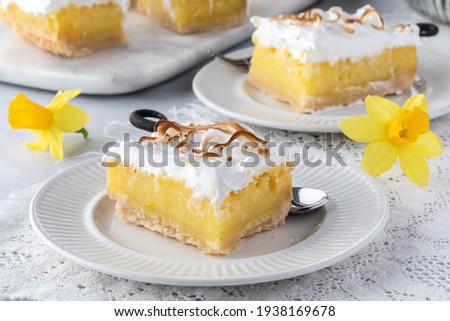 Close up of a serving of lemon meringue squares with other slices in behind.