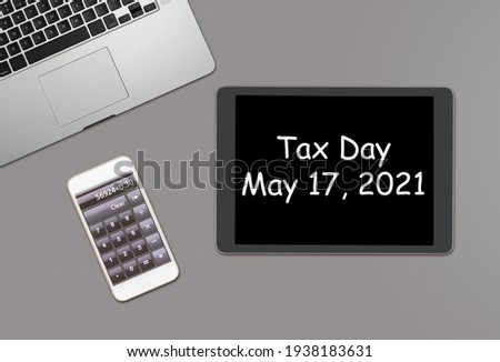 Overhead clean grey desk for laptop, smartphone and tablet computer with message for tax day 2021 as May 17 Royalty-Free Stock Photo #1938183631