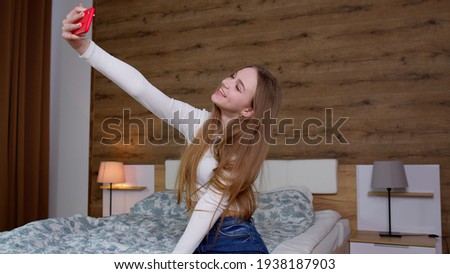 Happy young woman blogger influencer holding modern smart phone wave hand hello. Smiling cute vlogger girl looking at mobile make video call, shooting vlog taking selfie isolated on home background