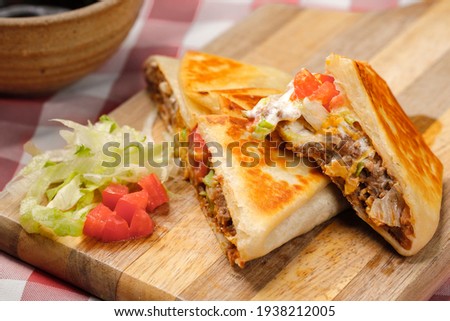 A close up photo of a homemade crunch wrap taco on a cutting board.