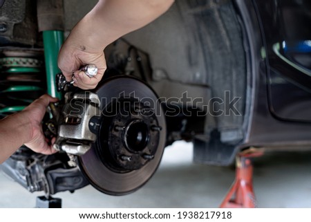 Technician is using a wrench to remove the locking nut of Brake caliper in service shop maintenance concept brake system 