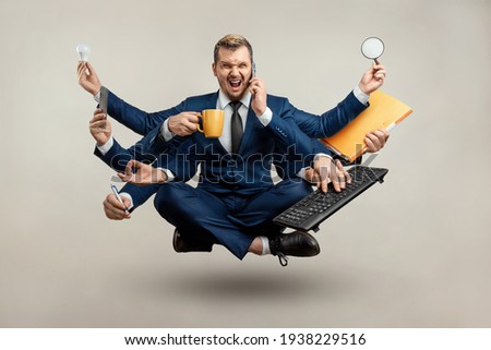 Businessman with many hands in a suit. Works simultaneously with several objects, a mug, a magnifying glass, papers, a contract, a telephone. Multitasking, efficient business worker concept Royalty-Free Stock Photo #1938229516