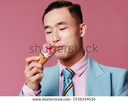 A man in a suit looks at an ice cream cone on a pink background