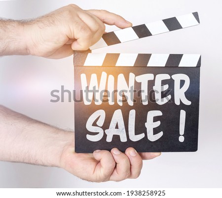 Business and finance concept. On a white background, a man holds a clapperboard in his hands on which it is written - WINTER SALE