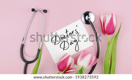 Tulips flowers and stethoscope with greeting card on a pink background. Doctor’s day is celebrated annually on March 30. It is a day to celebrate doctors, surgeons, nurses, physicians