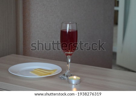 Red wine in a glass, cheese, a burning candle.