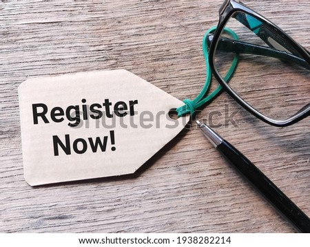 Phrase REGISTER NOW written on cupboard tag with eye glasses and a pen.