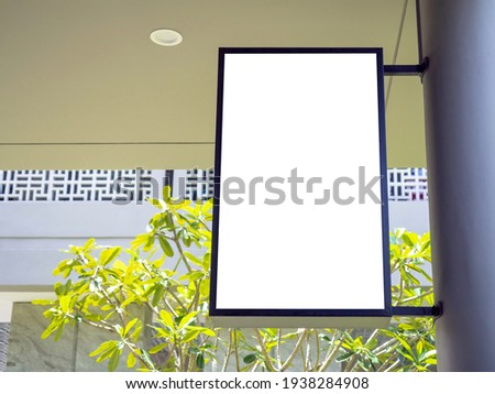 Blank hanging sign board or mockup light box showcase with black frame vertical style on big pole on the ground floors in the building for shop sign, information, text message and advertisement.