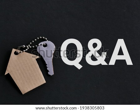 Property concept. Phrase Q and A on black background with house key chain.