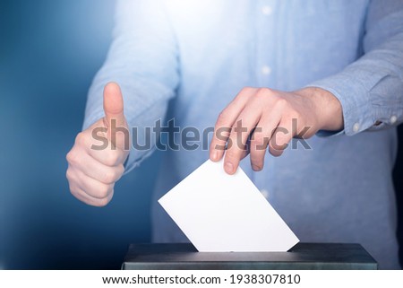 Hand of a voter putting vote in the ballot box. Election concept.