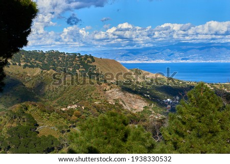 the green of Sicily overlooking the Strait, with valleys, villages and woods and clouds in the sky that cast shadows