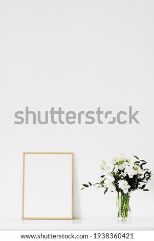 Golden vertical frame and bouquet of fresh flowers on white furniture, luxury home decor and design for mockup creations