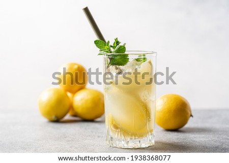 Citrus lemonade with mint and ice in glass with bamboo tube. Refreshing summer drink. White background, side view, close-up view