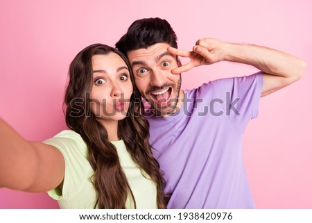 Self-portrait of beautiful friends friendship trendy cheerful couple embracing showing v-sign pout lips isolated over pink pastel color background