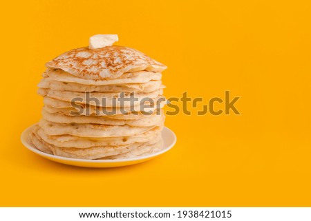 Staple of yeast fluffy pancakes with butter. Spring holiday Traditional Russian Shrovetide Maslenitsa week or pancake tuesday holiday. american crepes isolated on yellow background Royalty-Free Stock Photo #1938421015