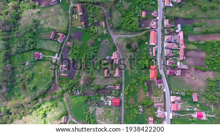 Aerial top view of a countryside village in Romania. Rural countryside landscape were the hamlet is located on a hilly region populated by trees. Royalty-Free Stock Photo #1938422200
