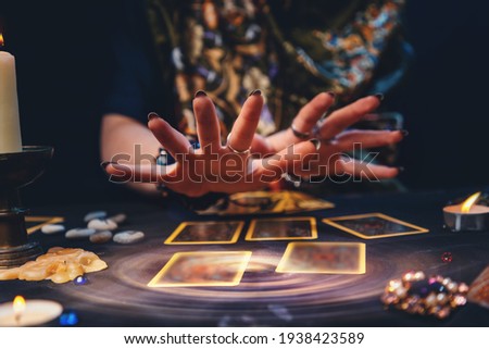 Astrology. The sorceress conjures over the tarot cards spread out on the table. Hands close-up. The concept of magic and esotericism. Royalty-Free Stock Photo #1938423589