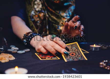A sorceress lays out fortune-telling cards tarot on the table. Hands close-up. The concept of card reading, magic and esotericism. Royalty-Free Stock Photo #1938423601