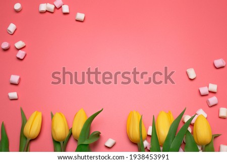 Yellow tulips and marshmallows on the pink background, with free space for text.