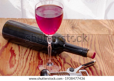 a glass of dry red wine a bottle and a corkscrew on the kitchen table. High quality photo